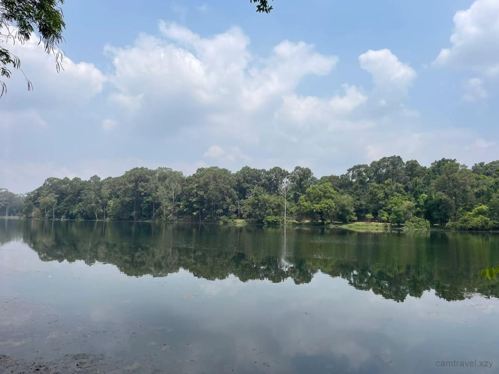 Serene reflection of trees in the vast Angkor Wat moat water